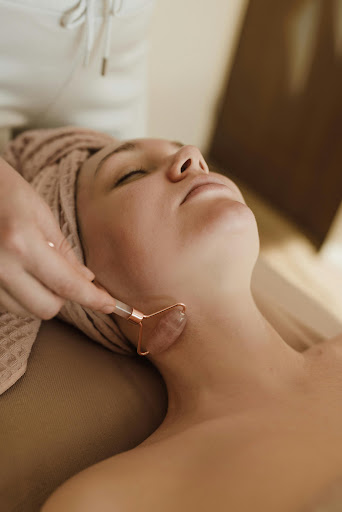 Professional facial treatment using a rose quartz crystal roller for skin rejuvenation